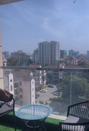 Ein Balkon mit Blick auf eine Stadtansicht, darunter Wohnhäuser und ein hohes Gebäude.