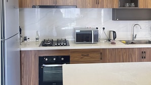 A modern kitchen with wooden cabinets, a stainless steel refrigerator, a microwave, a gas stove, and a dishwasher. - Luxury 2-bedroom, Modern Apartment, Elegant, Spacious in Kilimani Nairobi (Nairobi)
