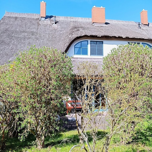 Ein Haus mit Strohdach, Fenster und Schornstein.