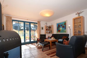 Ein Wohnzimmer mit Sofa, Sesseln, Couchtisch, Bücherregal und einem Bild an der Wand.