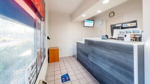 En reception med skranke, et ur, en skærm og et vindue med udsigt til det frie.