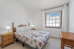 A bedroom with a bed, two bedside tables with lamps, a window, and a wooden chair. - Charming Bungalow Rental in Abades, Spain - Perfect Family Retreat (Abades)