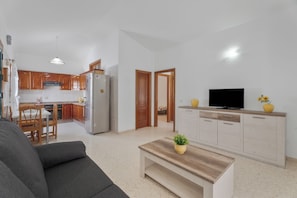 A modern living room with a sofa, a coffee table, and a TV on a wooden cabinet. - Charming Bungalow Rental in Abades, Spain - Perfect Family Retreat (Abades)