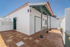 A building with a tiled roof, a covered patio area, and a door with a window. - Charming Bungalow Rental in Abades, Spain - Perfect Family Retreat (Abades)