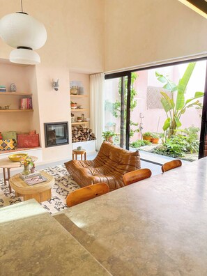 Uma sala de estar moderna com um sofá de couro, uma televisão e uma grande janela com vista para um jardim.