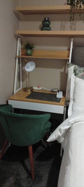 Una habitación pequeña con escritorio, silla y cama.