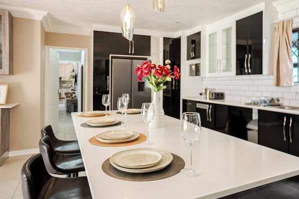 A modern kitchen with a central island, black cabinets, and a white countertop.