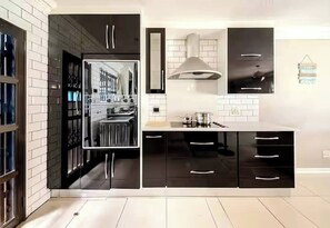 A modern kitchen with black cabinets, a stainless steel range, and a large window.