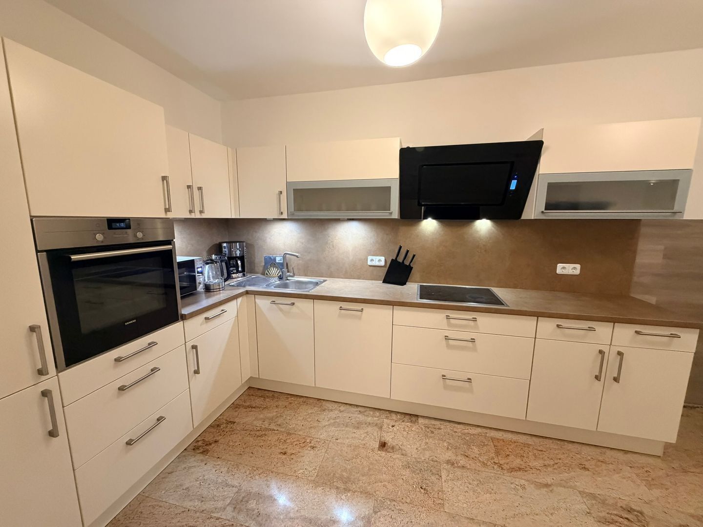 A modern kitchen with a built-in oven, microwave, and a large window above the sink.