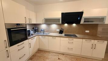 A modern kitchen with a built-in oven, microwave, and a large window above the sink.