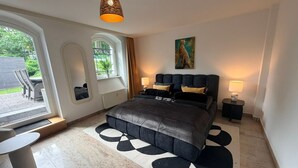 Una camera da letto moderna con un letto, un comodino, una lampada, un quadro e vista sull'esterno.