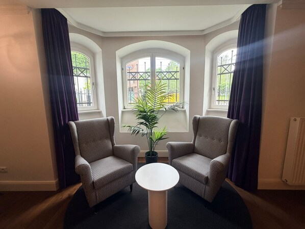 A room with two armchairs, a small round table, and a view through a bay window. - Top Premium 250-square-meter Villa Historica apartment with a garden—central, quiet, (Rostock)