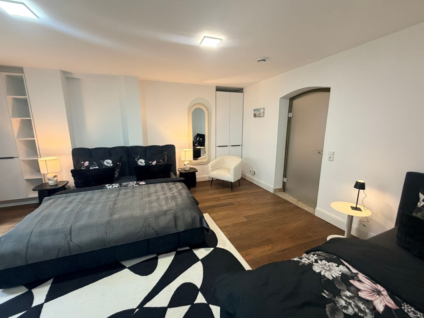 Ein modernes Schlafzimmer mit Bett, Nachttischen, einem Sessel und einem Kleiderschrank.