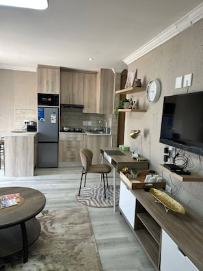 Eine moderne Küche mit Holzschränken, einer eingebauten Mikrowelle und einem Kühlschrank.