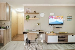 A modern kitchen with wooden cabinets, a built-in stove, and a dining area with a table and chairs. - Executive en-Suite, cozy, comfy and spacious (Johannesburg South)