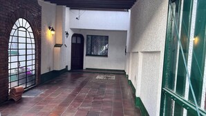 A covered outdoor area with a tiled floor, a brick archway, a door, and a window with a metal grid. - The House at north of Bogota (Bogotá)