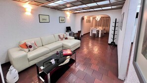 A living room with a sectional sofa, a glass coffee table, and a dining area with a chandelier. - The House at north of Bogota (Bogotá)