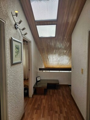 Ein schmaler Korridor mit Holzboden, einem Oberlicht und einem gerahmten Bild an der Wand.