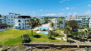 A modern hotel complex with multiple white buildings, a central swimming pool, and surrounding palm trees. - Relax in Style Oceanfront 3 Bedroom Apartment in Sosua (Sosúa)