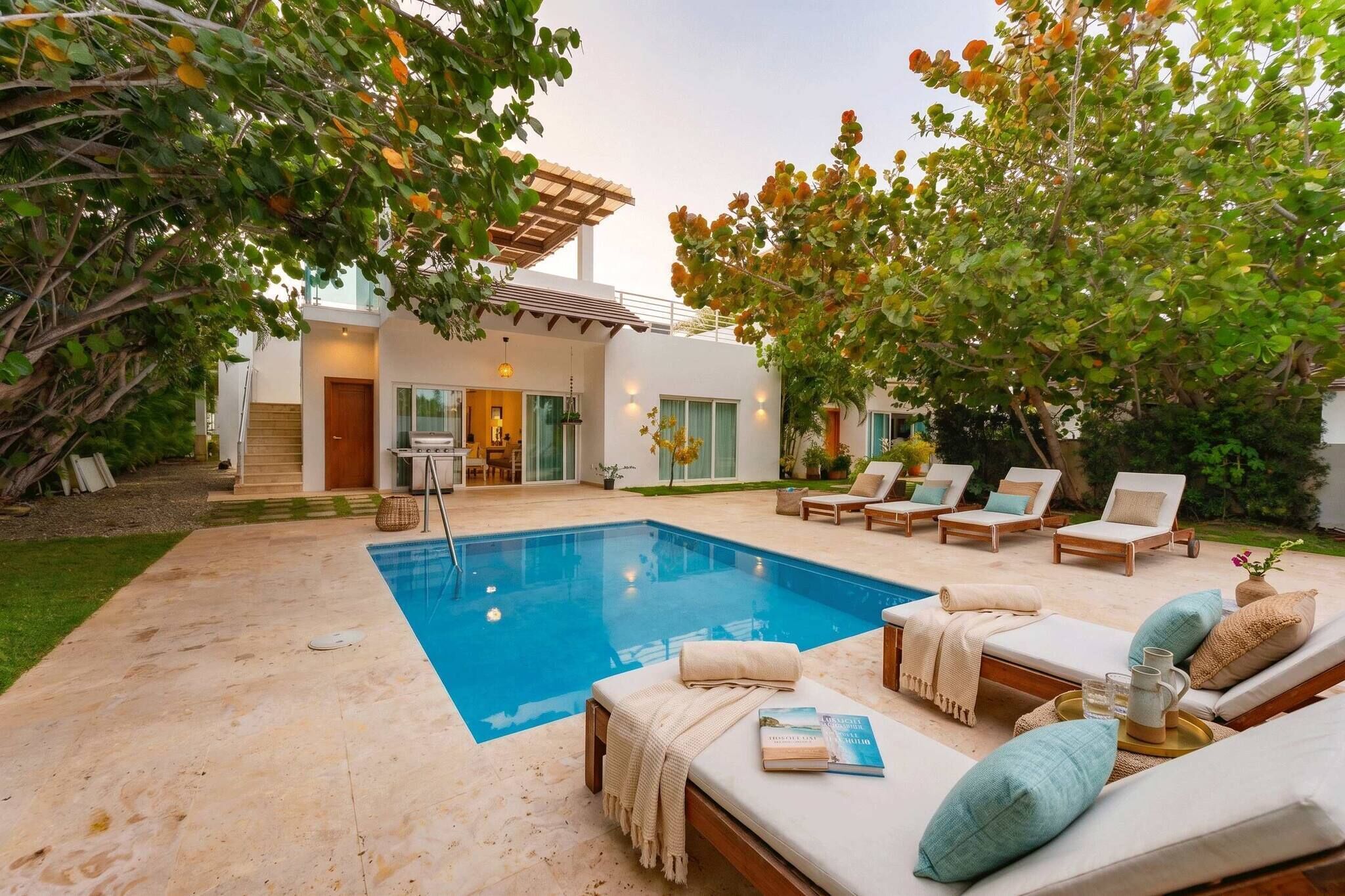 Une maison moderne dotée d’une piscine, de chaises longues et d’un patio couvert.