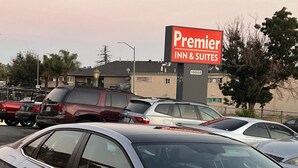 A parking lot with multiple cars, a sign for Premier Inn & Suites, and a building in the background.