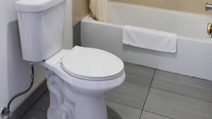 Et badeværelse med toilet, badekar og bruseforhæng.