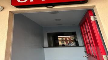 An office entrance with a red door and a window overlooking a building.