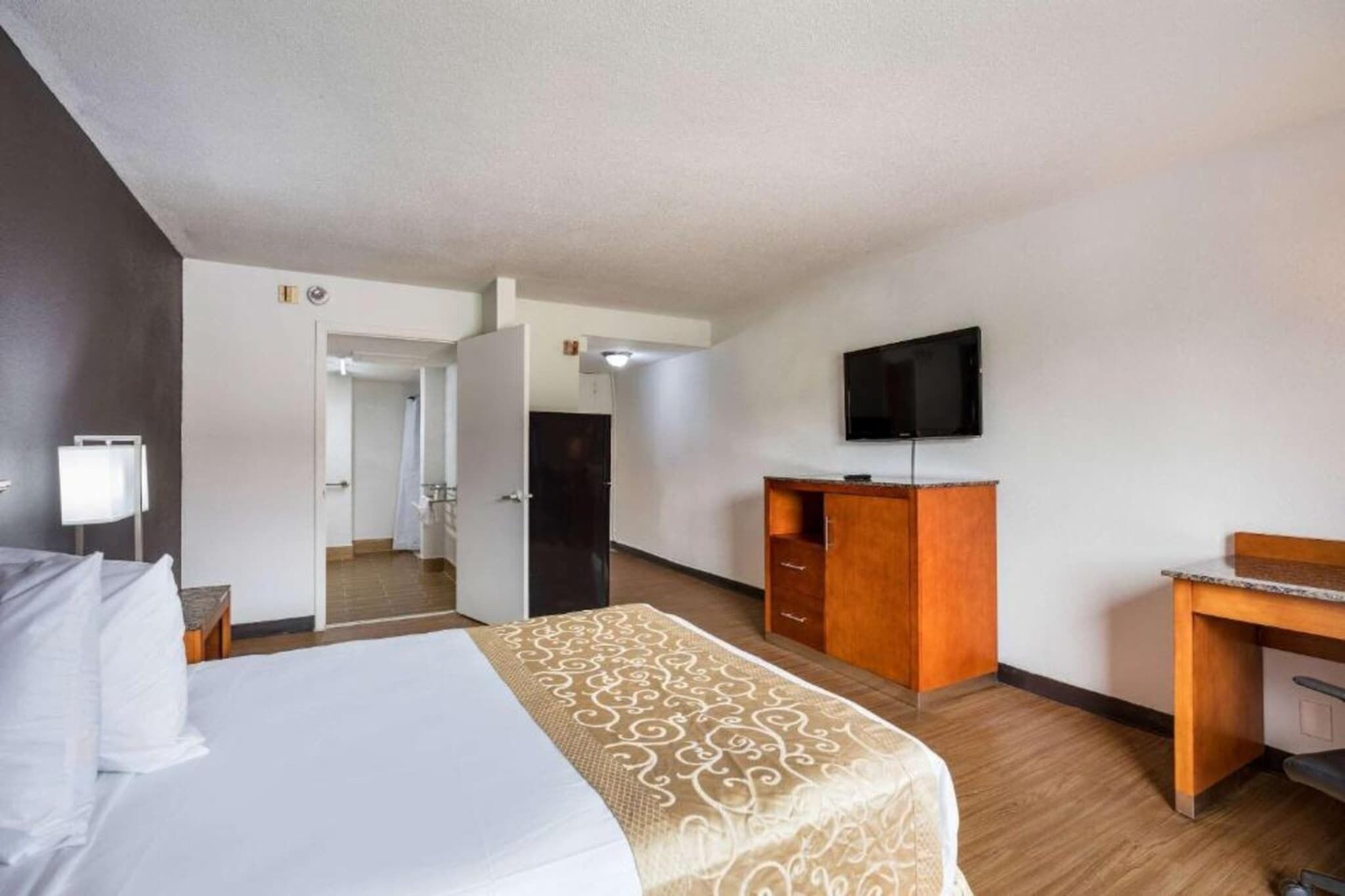 Une chambre d’hôtel équipée d’un lit, d’un bureau, d’une télévision et d’une armoire.