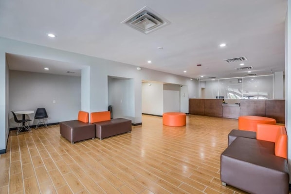 Um hall amplo com piso de madeira, áreas de estar e um balcão de recepção.