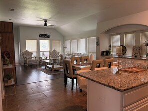 A spacious living room with a large white sofa, a dining area with a glass-top table, and a kitchen with granite countertops. - Spacious Executive Retreat - Sleeps 8+ (Midlothian)