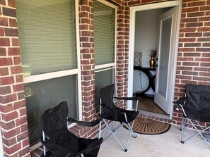 A covered patio area with two chairs, a door leading inside, and a small table with a vase. - Spacious Executive Retreat - Sleeps 8+ (Midlothian)
