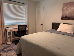A bedroom with a bed, a desk, and a chair.