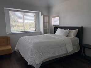 A bedroom with a bed, two windows with blinds, a chair, and a small table. - Spacious Executive Retreat - Sleeps 8+ (Midlothian)