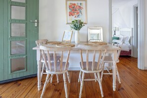 Una mesa de comedor con cuatro sillas, un florero con flores y un cuadro en la pared.