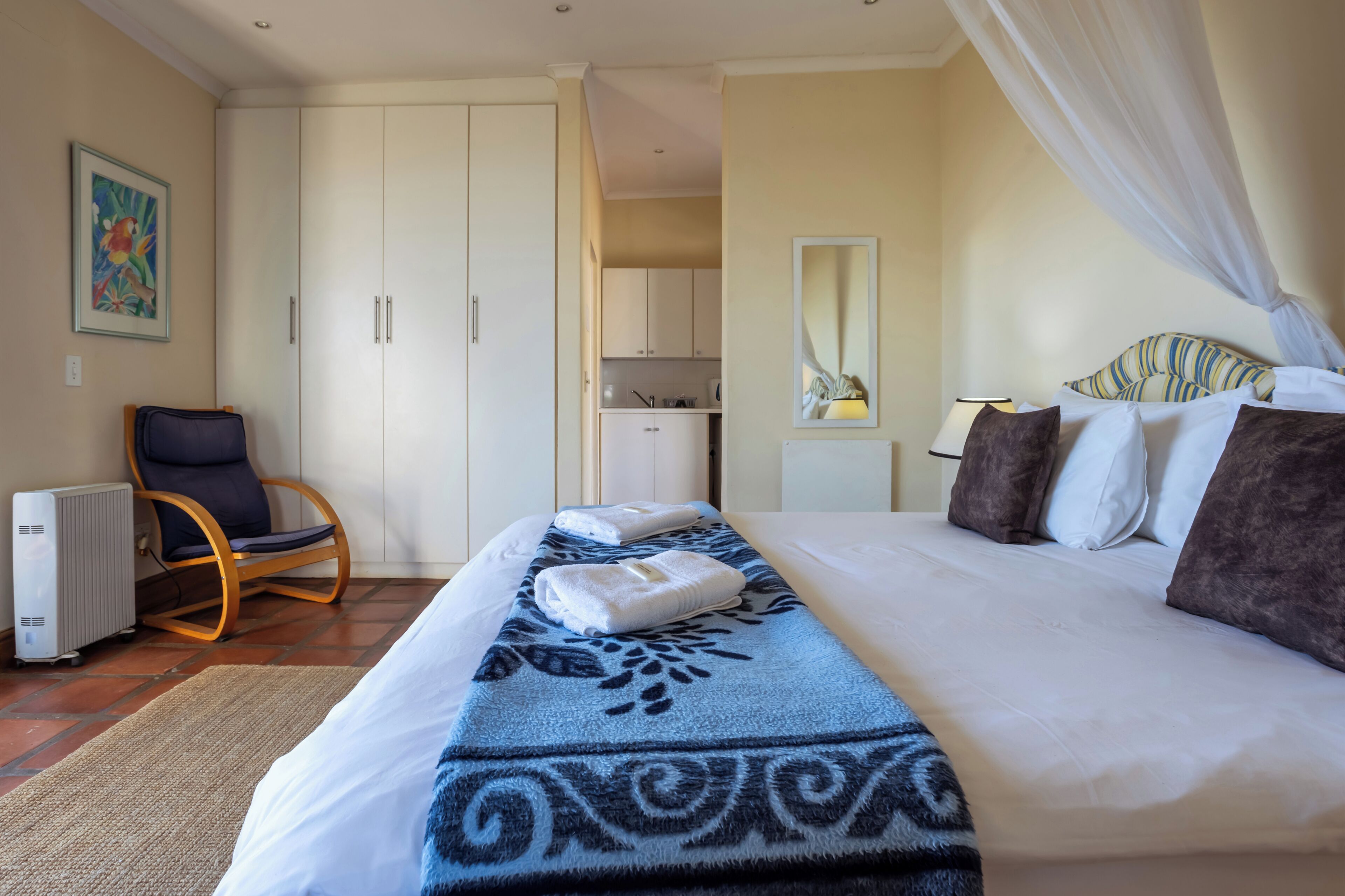 Ein Hotelzimmer mit Bett, Stuhl, Heizkörper, Küchenzeile und Spiegel.