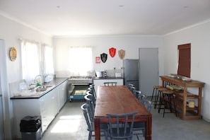A kitchen with a wooden table and chairs, a refrigerator, and a sink. - Goedgedacht Farm (WC)