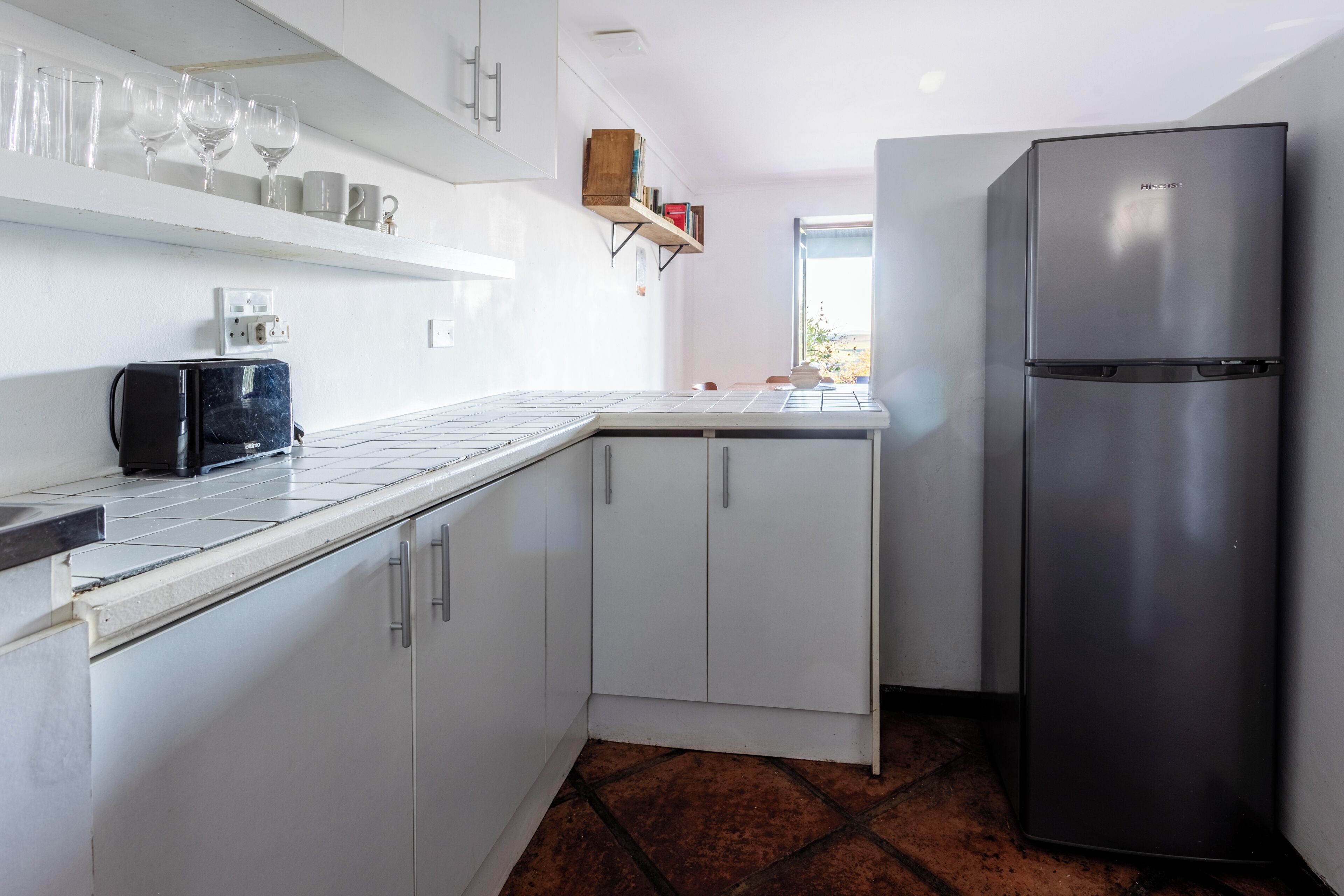 A compact kitchen with white cabinets, a stainless steel refrigerator, and a countertop with a toaster.