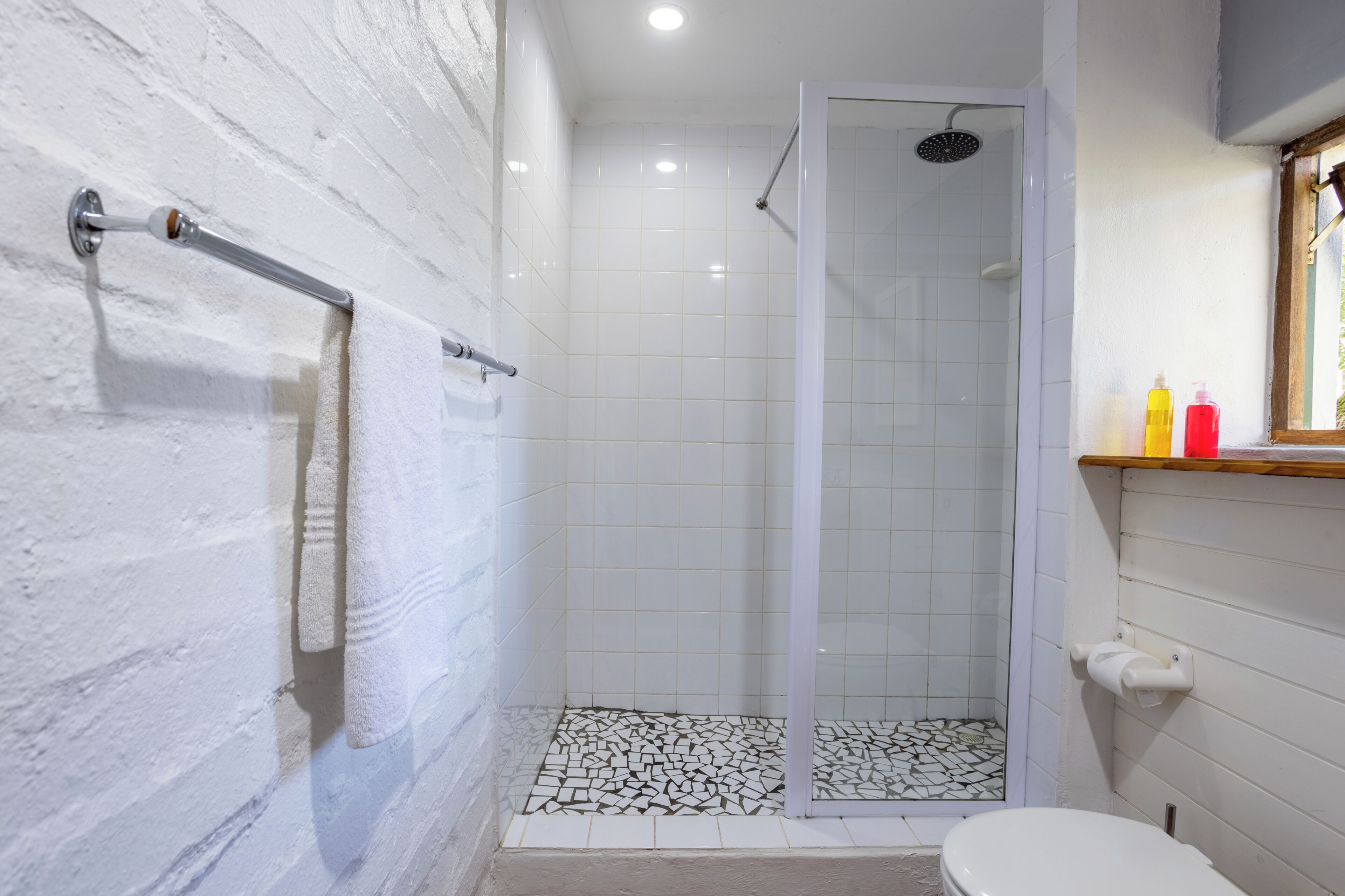A bathroom with a shower, a toilet, and a sink with toiletries.