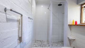 A bathroom with a shower, a toilet, and a sink with toiletries.