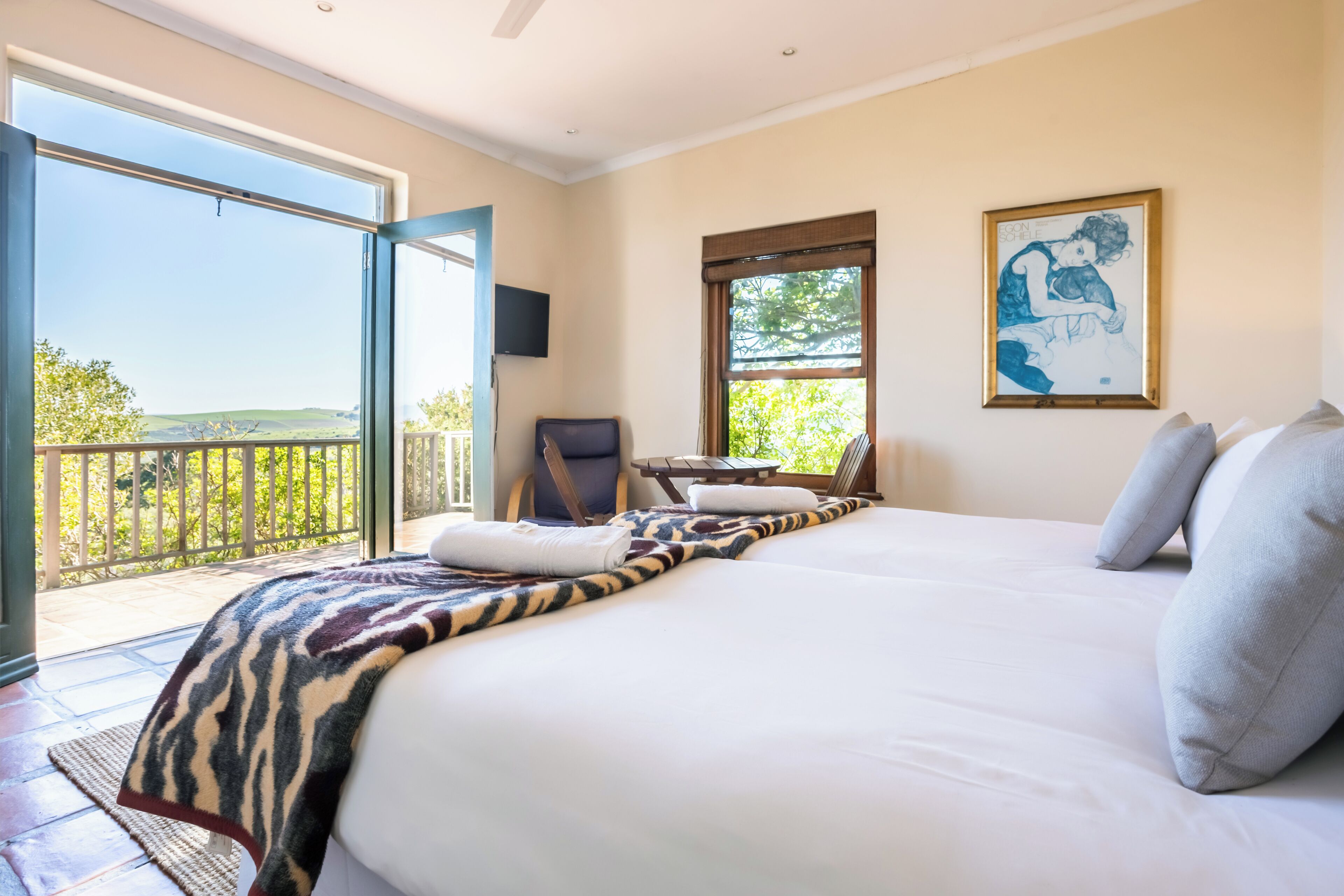 Un dormitorio con una cama grande, una silla, un televisor y un balcón con vistas.