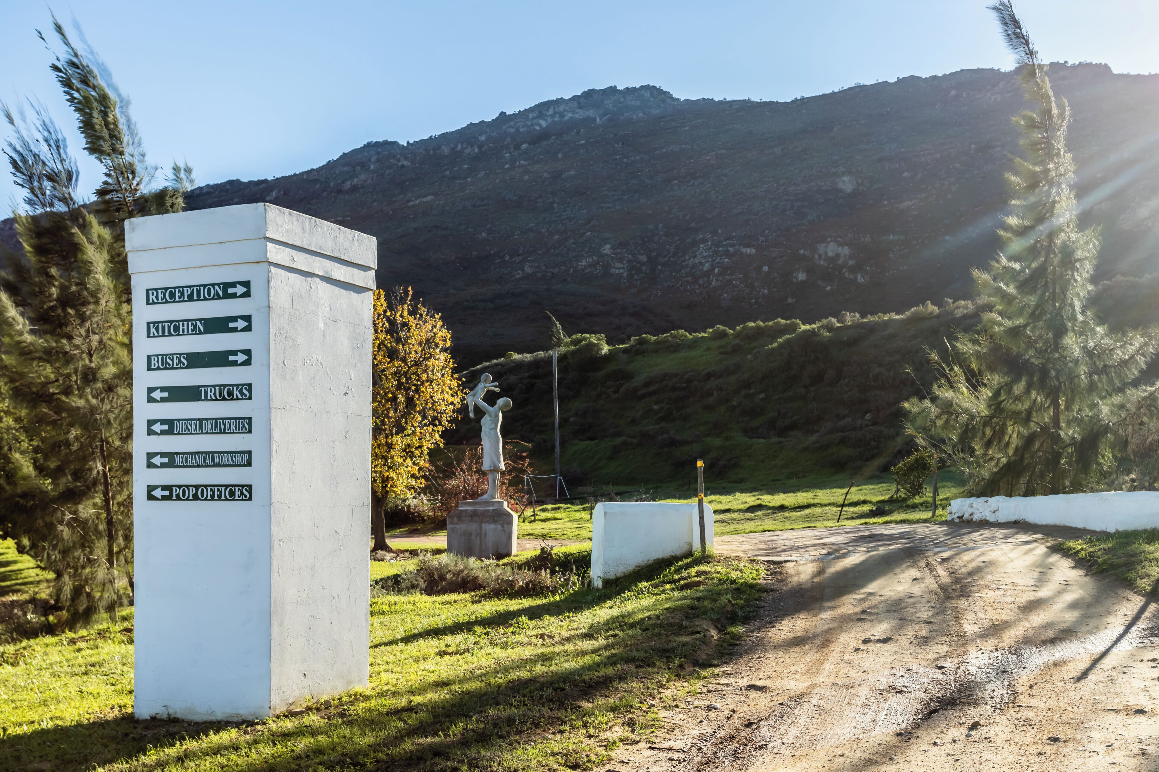 Een richtingsbord met pijlen naar verschillende voorzieningen, zoals receptie, keuken, bussen, vrachtwagens, dieselleveringen, een mechanisch werkplaats en kantoorruimtes.