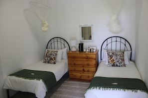 A bedroom with two single beds, a wooden dresser, a mirror, and mosquito nets. - Goedgedacht Farm (WC)