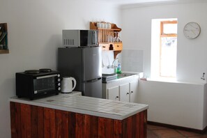 A kitchen with a microwave, toaster, refrigerator, and wooden cabinets. - Goedgedacht Farm (WC)