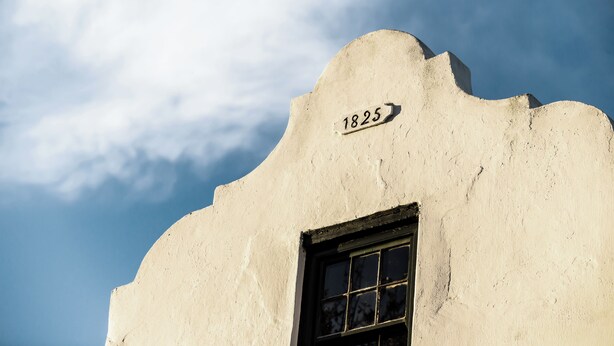 A building with a unique architectural style, a window, and a number plaque indicating the year 1825.