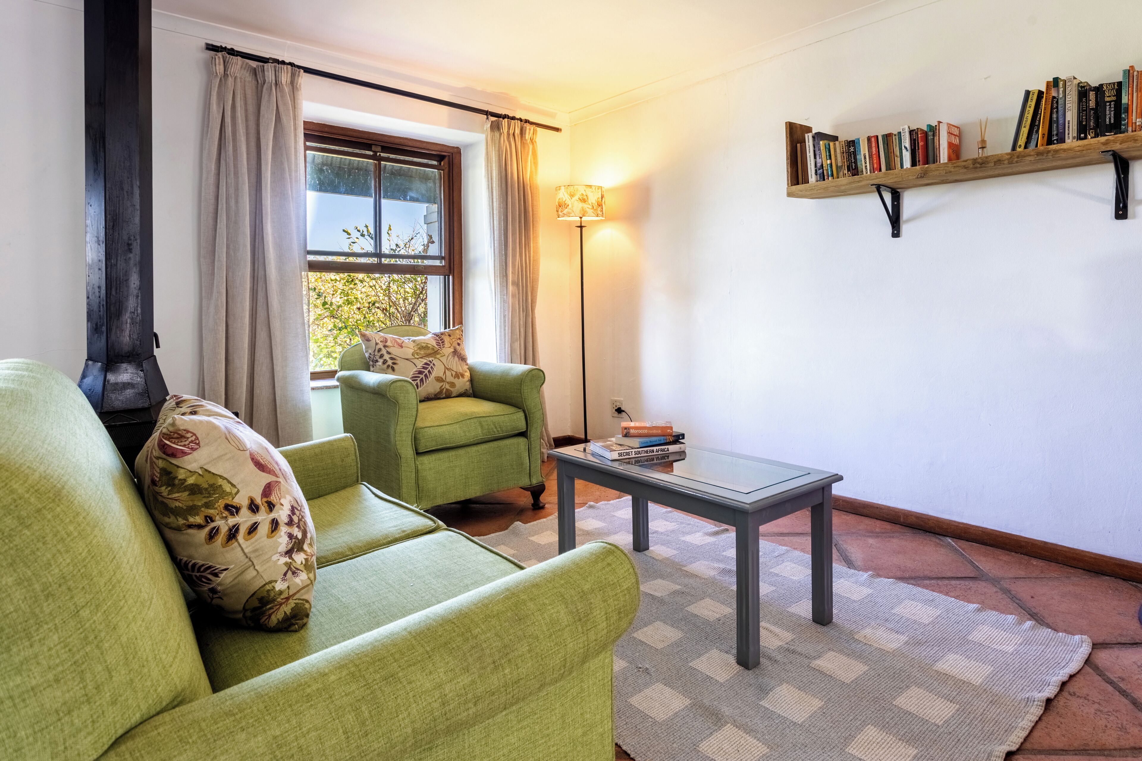 A living room with a sofa, a chair, a coffee table, a lamp, and a bookshelf.