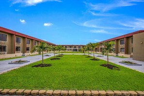 A hotel with a central courtyard, multiple floors, and a consistent architectural style. - 2 Full Bed  with kitchenette Non-Smoking (Orlando FL)