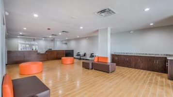 Un vestíbulo amplio con suelo de madera, zonas de estar y un mostrador de recepción.