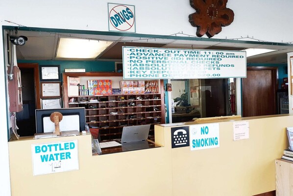 Eine Apotheke mit Schild, das Abholzeiten, Rauchverbot und eine Abteilung für abgefülltes Wasser anzeigt.