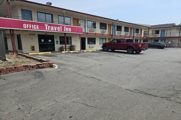 A two-story motel with a red awning labeled 'OFFICE Travel Inn.'