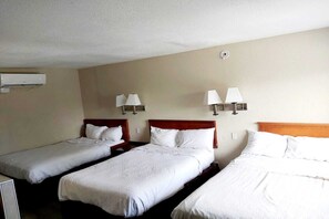 A hotel room with three single beds, each with a wooden headboard, white bedding, and two wall-mounted lamps. - 3 Full bed|smoking|Omaha NE (Omaha NE)